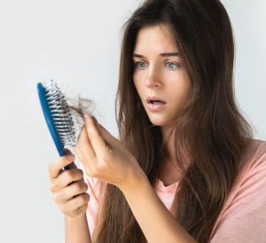 young woman worried hair loss comb